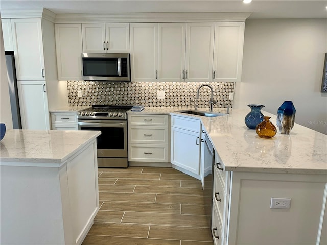 5760 Midnight Pass Rd Unit 307D, Sarasota, FL 34242 - kitchen featuring appliances with stainless steel finishes, a peninsula, wood finish floors, decorative backsplash, and white cabinetry