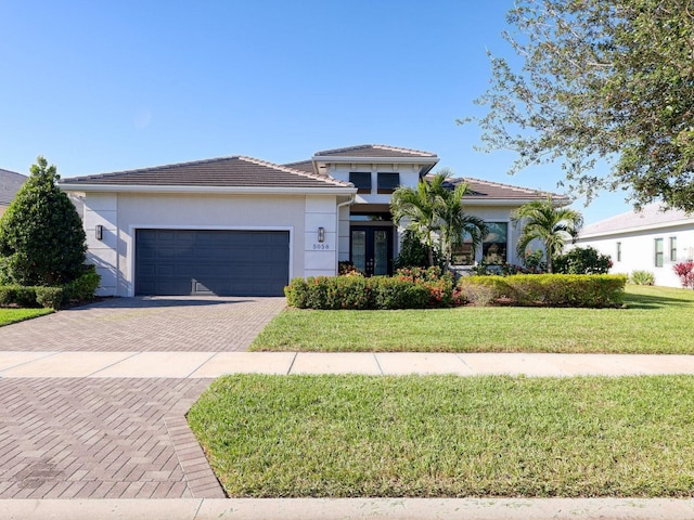 view of front of home with a garage, a front yard, and french doors