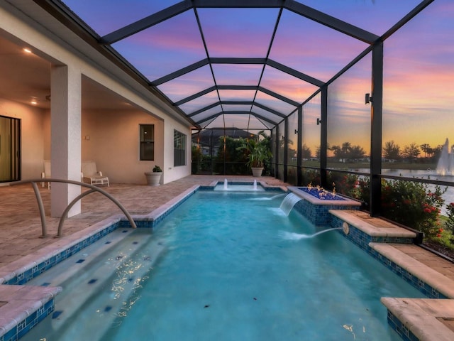 pool at dusk featuring glass enclosure, pool water feature, a patio area, and a jacuzzi