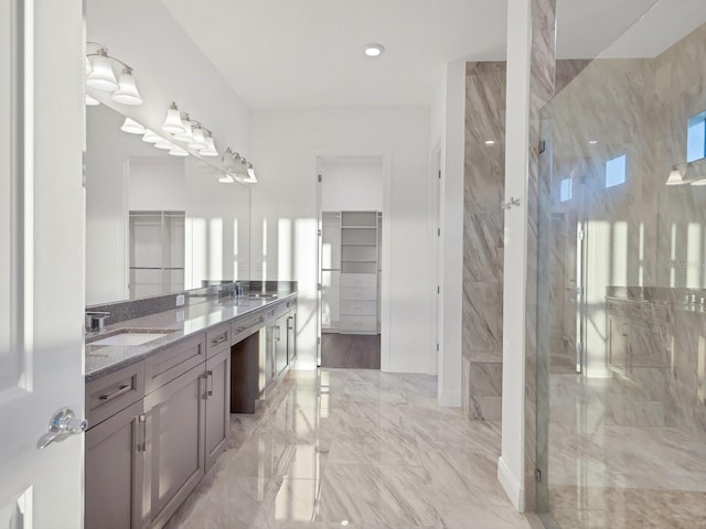 full bathroom with a marble finish shower, a sink, marble finish floor, and double vanity