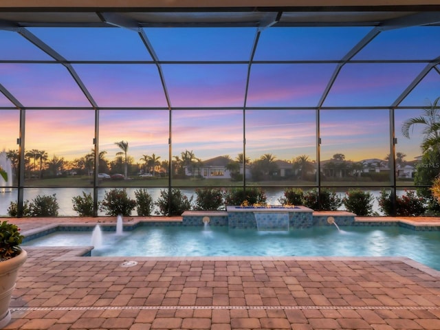 pool with a patio, glass enclosure, a hot tub, and a water view