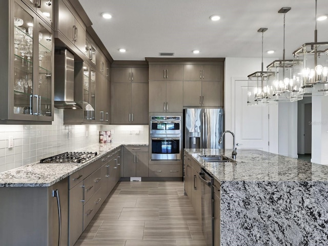 kitchen with backsplash, wall chimney exhaust hood, stainless steel appliances, and a sink