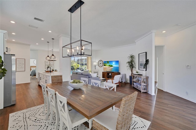 dining room with dark hardwood / wood-style flooring, a textured ceiling, crown molding, sink, and an inviting chandelier