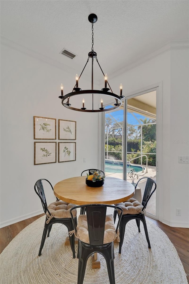 dining room featuring crown molding, hardwood / wood-style floors, a chandelier, and a textured ceiling