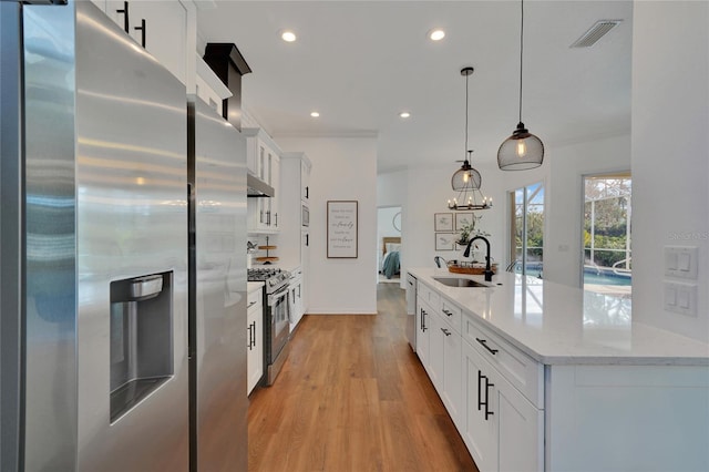 kitchen featuring pendant lighting, sink, light wood-type flooring, appliances with stainless steel finishes, and white cabinetry