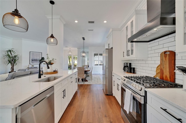 kitchen featuring white cabinets, appliances with stainless steel finishes, wall chimney exhaust hood, and sink