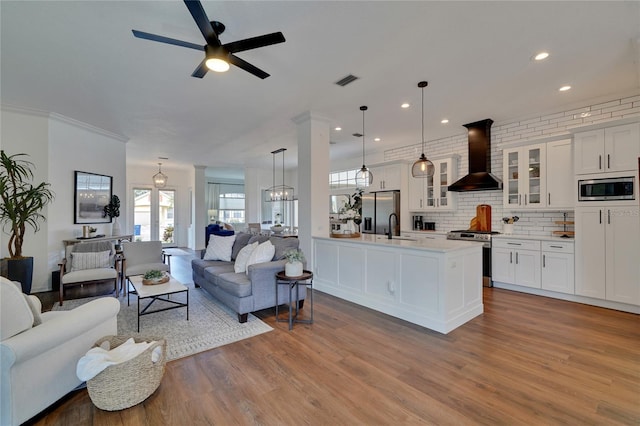 living room with ceiling fan, light hardwood / wood-style floors, ornamental molding, and sink