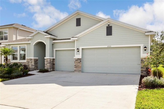 16926 Harvest Moon Way, Bradenton, FL 34211 - view of front facade with an attached garage, stone siding, driveway, and stucco siding