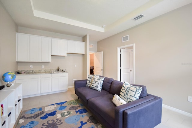 16926 Harvest Moon Way, Bradenton, FL 34211 - living room featuring a tray ceiling, light tile patterned floors, and baseboards