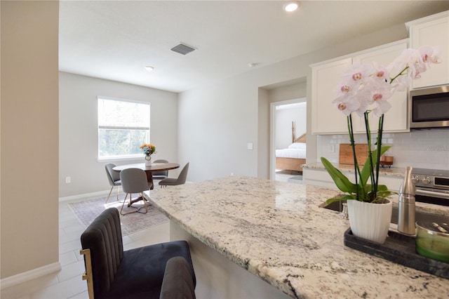 16926 Harvest Moon Way, Bradenton, FL 34211 - kitchen with stainless steel microwave, light stone counters, baseboards, white cabinets, and recessed lighting