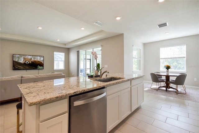 16926 Harvest Moon Way, Bradenton, FL 34211 - kitchen with stainless steel dishwasher, a sink, light stone counters, white cabinets, and open floor plan
