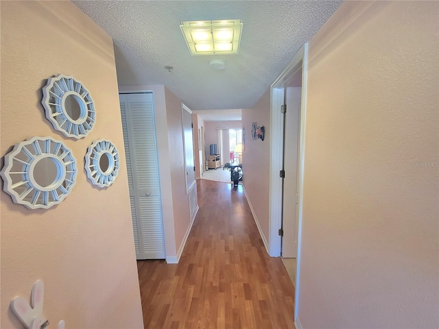 corridor featuring a textured ceiling and light hardwood / wood-style flooring