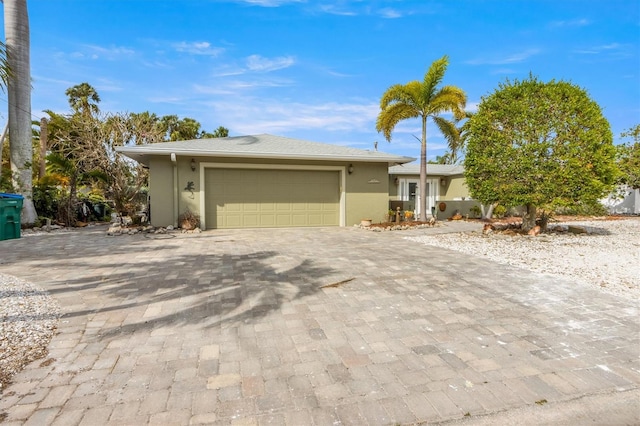 ranch-style house with decorative driveway, an attached garage, and stucco siding