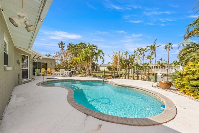 view of pool with a water view and a patio