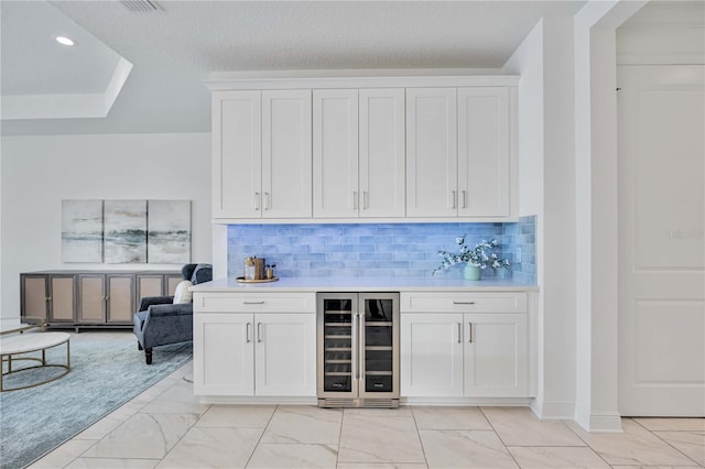 bar with tasteful backsplash, wine cooler, and white cabinets