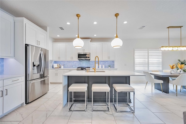 kitchen featuring white cabinets, decorative light fixtures, and appliances with stainless steel finishes