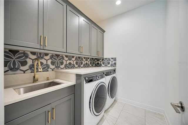 clothes washing area with washing machine and clothes dryer, sink, and cabinets