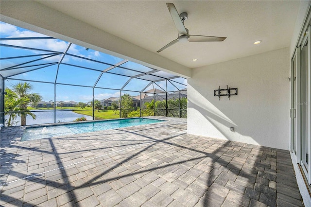 view of pool with glass enclosure, ceiling fan, a water view, and a patio