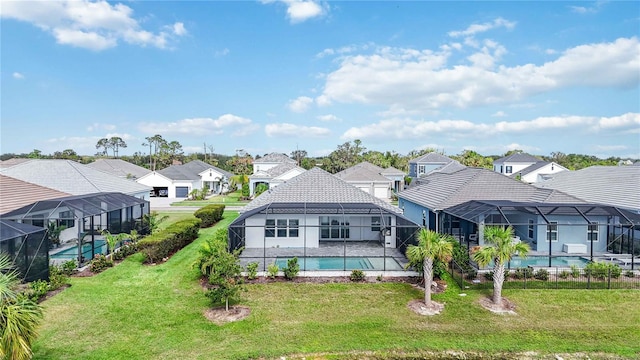 rear view of property featuring a lanai and a lawn