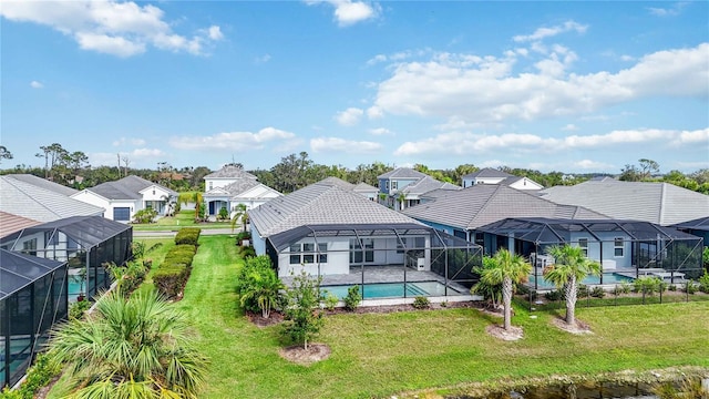 rear view of property with a lanai and a lawn