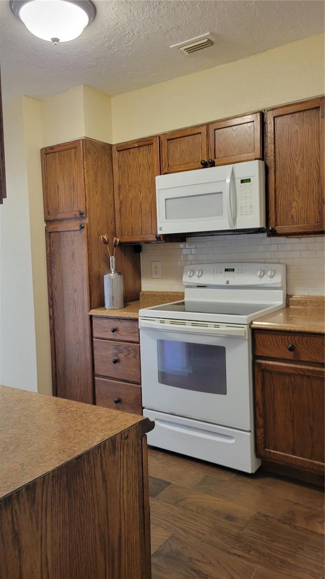 kitchen featuring dark hardwood / wood-style floors, white appliances, and tasteful backsplash