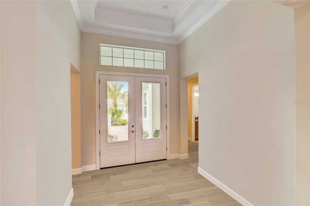 foyer entrance with light hardwood / wood-style floors, ornamental molding, a wealth of natural light, and french doors