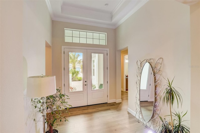 foyer featuring ornamental molding, light hardwood / wood-style flooring, a wealth of natural light, and french doors