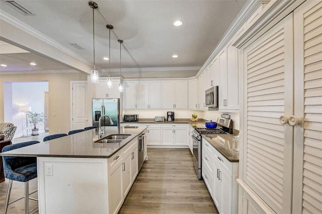 kitchen with white cabinetry, sink, hanging light fixtures, a center island with sink, and appliances with stainless steel finishes