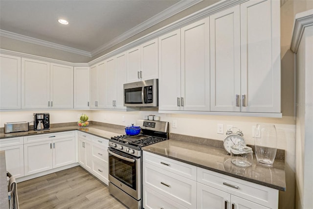 kitchen with white cabinetry, ornamental molding, appliances with stainless steel finishes, and light hardwood / wood-style flooring