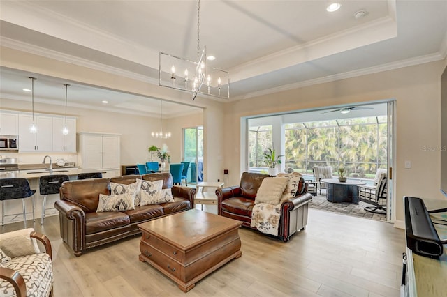 living room with a raised ceiling, ornamental molding, and light wood-type flooring