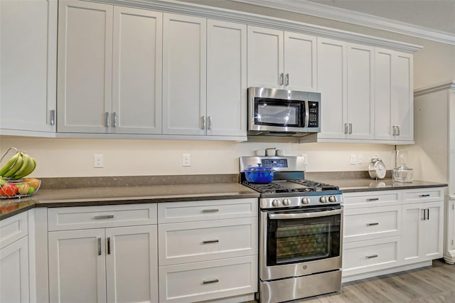 kitchen featuring white cabinets, light wood-type flooring, crown molding, and appliances with stainless steel finishes