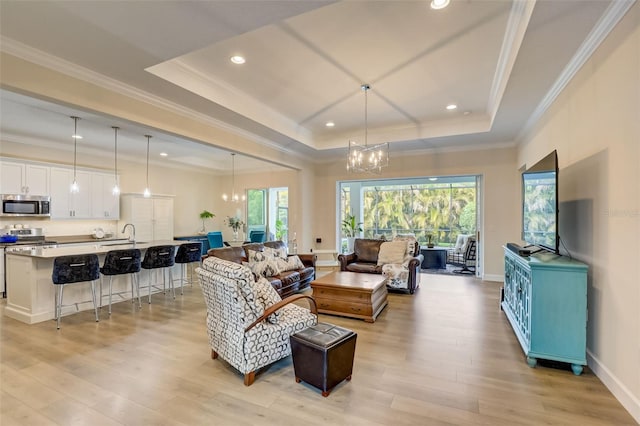 living room featuring crown molding, a chandelier, and light wood-type flooring