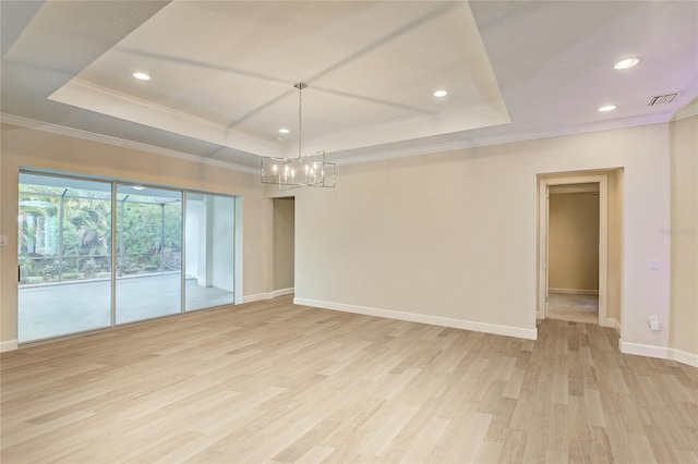 unfurnished room with light hardwood / wood-style floors, crown molding, a tray ceiling, and a notable chandelier