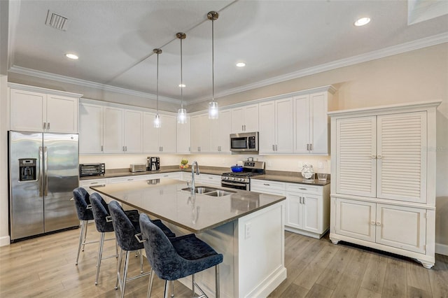 kitchen featuring appliances with stainless steel finishes, decorative light fixtures, white cabinetry, and sink