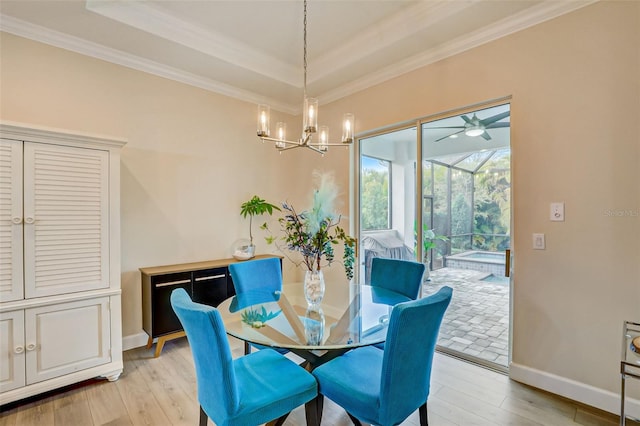 dining room featuring ceiling fan with notable chandelier, light wood-type flooring, a raised ceiling, and crown molding