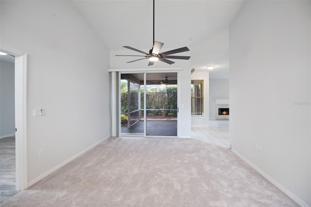 unfurnished room featuring high vaulted ceiling, carpet floors, a fireplace, a ceiling fan, and baseboards