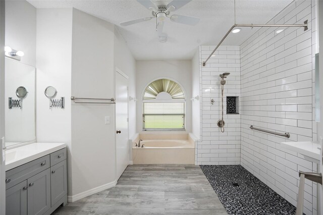 bathroom with a ceiling fan, a tile shower, vanity, wood finished floors, and a bath