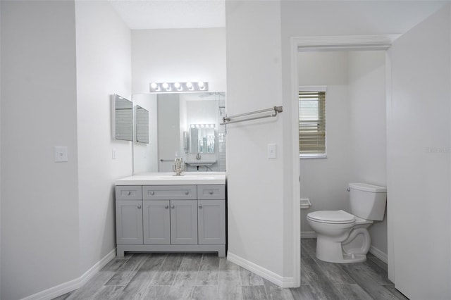 bathroom featuring vanity, wood finished floors, toilet, and baseboards