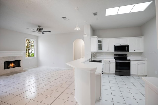 kitchen featuring visible vents, stainless steel microwave, a sink, black range with electric cooktop, and a peninsula