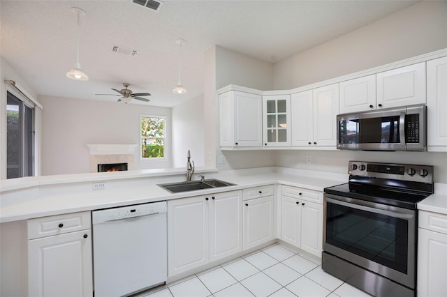 kitchen with visible vents, hanging light fixtures, stainless steel appliances, light countertops, and a sink