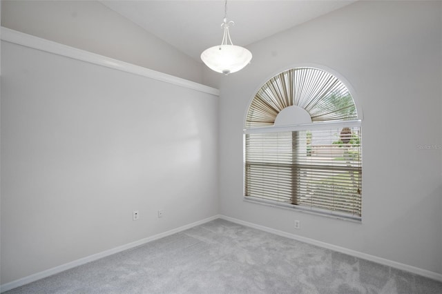 spare room with carpet, vaulted ceiling, and baseboards