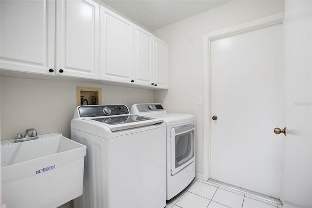 clothes washing area featuring light tile patterned floors, separate washer and dryer, a sink, and cabinet space