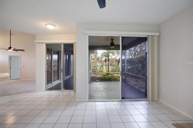 doorway featuring tile patterned flooring, a ceiling fan, and baseboards