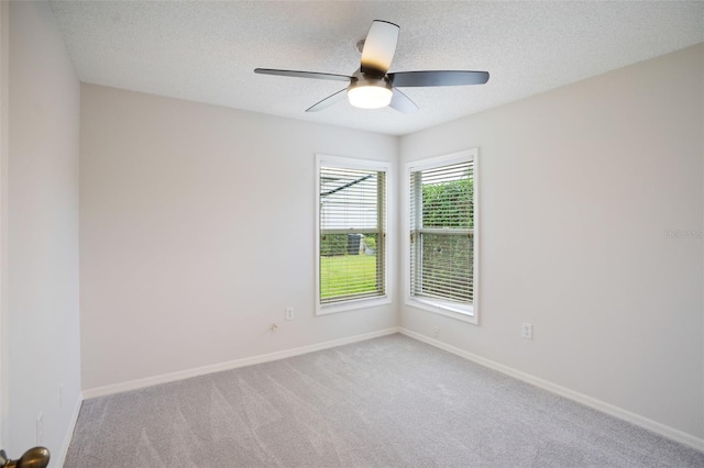 carpeted spare room with ceiling fan, baseboards, and a textured ceiling