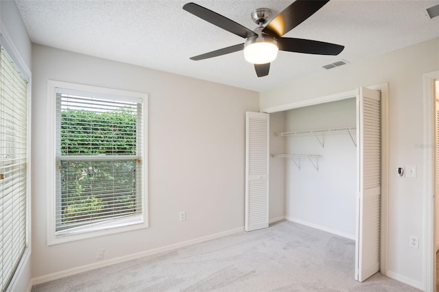 unfurnished bedroom featuring multiple windows, visible vents, and light colored carpet