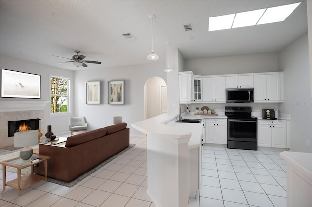 kitchen featuring a peninsula, range with electric stovetop, a sink, visible vents, and stainless steel microwave