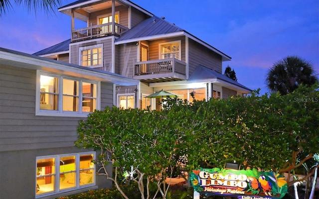 back house at dusk with a balcony