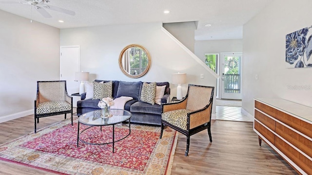 living room with a textured ceiling, light hardwood / wood-style flooring, and ceiling fan