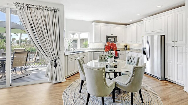 dining room with light wood-type flooring, plenty of natural light, and sink