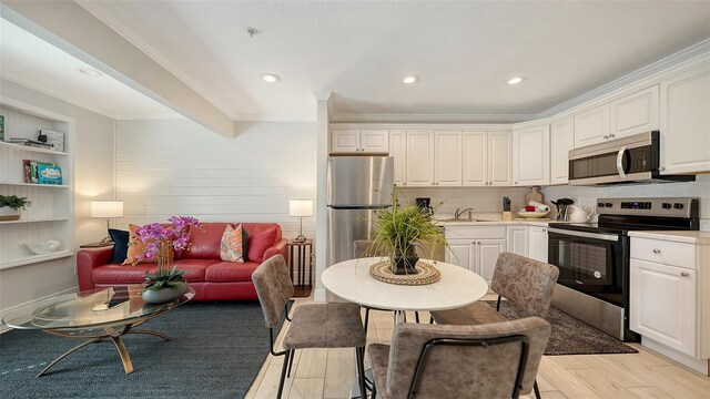 kitchen featuring white cabinets, stainless steel appliances, crown molding, and sink